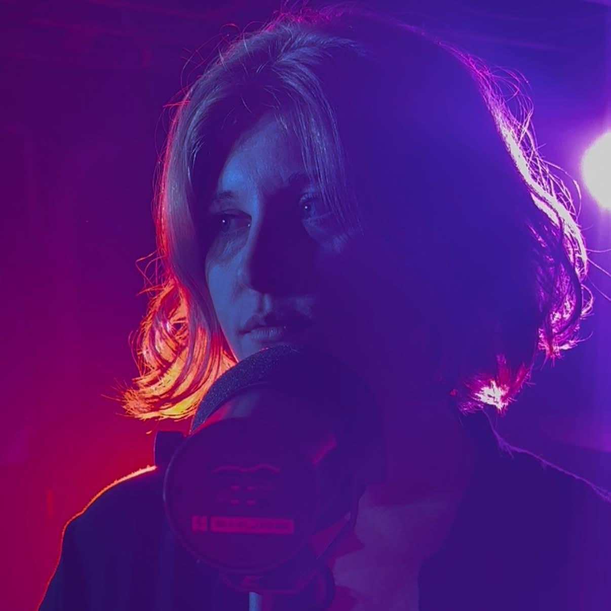 Maggie Moon singing under neon blue and pink stage lights